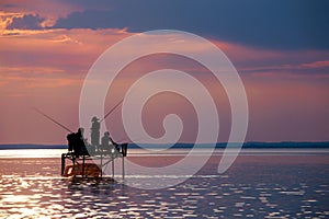 Anglers` silhouettes on a fishing stand at sunset at Lake Balat