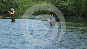 Angling, two men fishing on the river, standing in the water, a small current