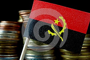 Angolan flag waving with stack of money coins