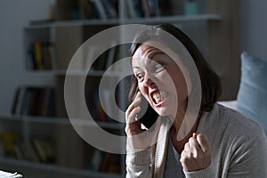 Angry adult woman calling on phone at night at home