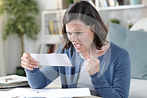 Angry adult woman looking at receipts at home