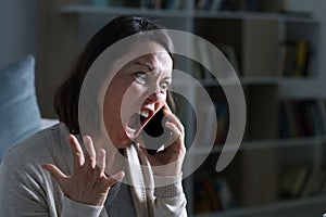 Angry adult woman screaming calling on phone at night at home