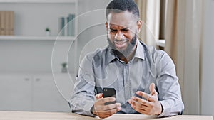 Angry African American ethnic bearded man boss businessman with mobile phone smartphone mistake failure reading bad news