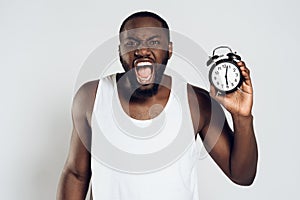 Angry African American man yells holding alarm photo