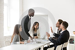 Angry African American shouting at Caucasian colleague blaming