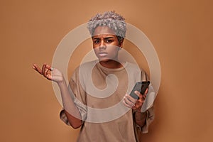 Angry African American young woman holding cellphone irritated by broken device