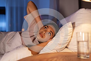 angry african woman lying in bed and closing ears