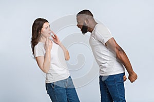 Angry afro guy emotionally shouting at his scared girlfriend, blaming her
