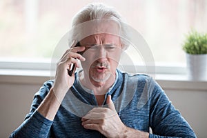 Angry aged man having discussion on cell phone