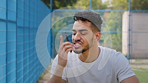 Angry aggressive annoyed young Middle eastern Arabic athlete in summer sportswear holding smartphone, worried furiously