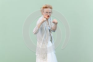 Angry aggressive attractive blonde woman clenching fists, being ready to attack.