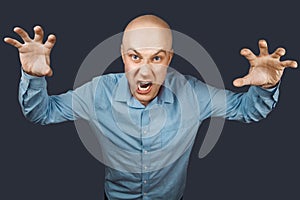 Angry aggressive bald man depicting nightmare on a dark background