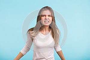 Angry aggressive woman with ferocious expression on blue background