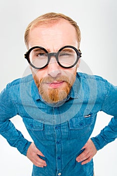 Angry amusing young man with beard in funny round glasses