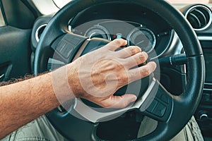 Angry and annoyed driver honking the car horn by pushing the button on steering wheel, pov image