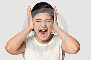 Angry annoyed Indian girl covering ears, screaming loud close up