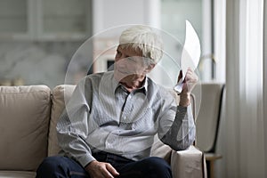 Angry annoyed older customer man holding paper documents, loan