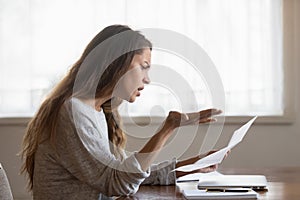 Angry annoyed woman reading bad news in letter, holding paper