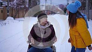 Angry Asian man in wheelchair arguing with Caucasian woman as lady walking away leaving. Portrait of sad depressed