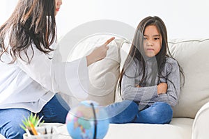 Angry asian mother sitting with little daughter , mom scolds for discipline bad behaviour capricious kid, family generations