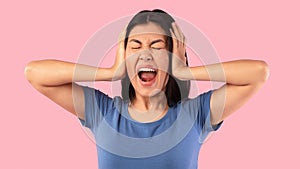 Angry asian woman covering her ears with hands and screaming