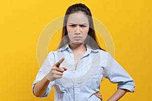 Angry asian woman feeling satisfied on the facial expression and pointing finger to camera isolated on yellow background studio