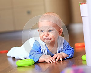 Angry baby boy learning to crawl annoyed