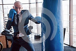 An angry bald businessman beats a boxing pear in the gym. concept of anger management