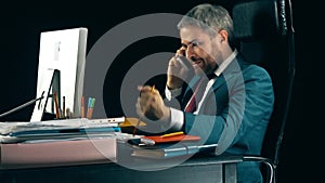 Angry bearded businessman having emotional stressful conversation on his cell phone. Black background. 4K video