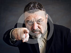 Angry bearded man in a black suit point a finger at you. Copy space. A gesture of choice.