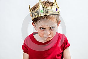 Angry beautiful spoiled kid wearing king crown facing unhappy parenthood photo