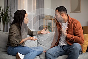 Angry Black Couple Having Quarrel Sitting On Sofa At Home