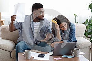 Angry black man scolding wife for huge credit card bills at home
