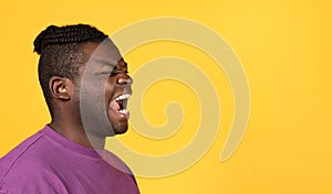 Angry black man shouting towards free space over yellow background