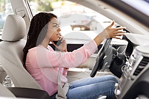Angry black woman talking on cell phone while driving car