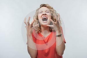 Angry blonde woman screaming and raising hands in anger. Negative emotion, facial expression concept