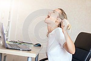 Angry blonde woman working on laptop at home and screaming She`s upset. Freelance, work at home concept