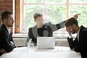 Angry boss firing employee with hand gesture at office meeting