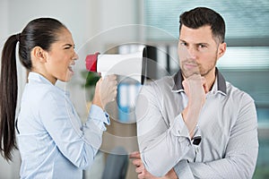 angry boss with megaphone screaming at oblivious employee in office