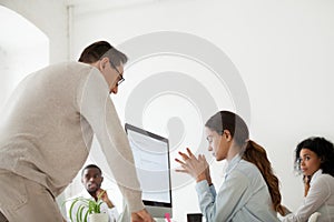 Angry boss scolding or firing upset intern in multiracial office