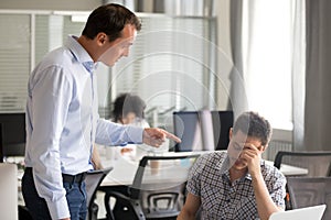Angry boss scolding rebuking incompetent male office worker at w photo