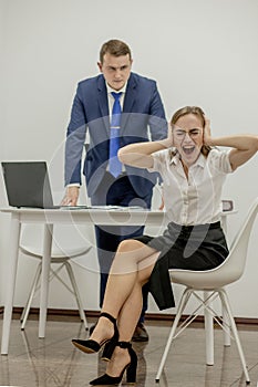 Angry boss yelling at his young employee, she is stressed and feeling frustrated: hostile boss and mobbing concept