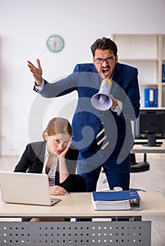 Angry boss and young female employee at workplace