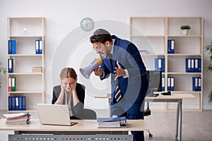 Angry boss and young female employee at workplace