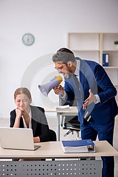 Angry boss and young female employee at workplace