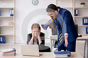 Angry boss and young female employee at workplace