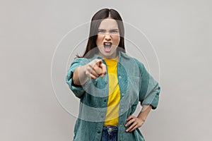 Angry bossy woman with dark hair pointing to camera with aggrssive expression, making choice.