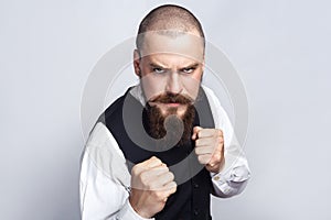 Angry boxing. Handsome businessman with beard and handlebar mustache looking at camera with angry face and fist.