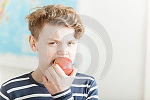 Angry boy biting into an apple