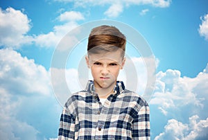 Angry boy in checkered shirt over blue sky